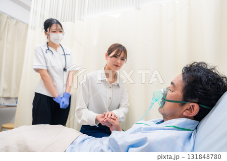 人工呼吸器をつけた家族のお見舞いをする若い女性 131848780