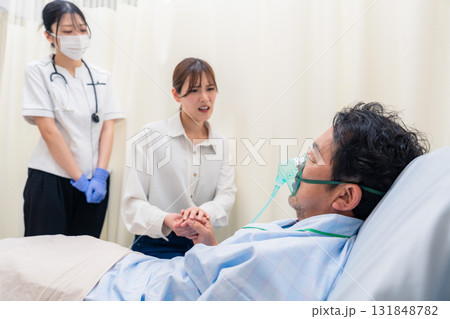 人工呼吸器をつけた家族のお見舞いをする若い女性 人工呼吸器をつけた家族のお見舞いをする若い女性 131848782