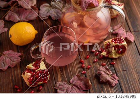 Autumn Beverage: Pomegranate Tea with Lemon and Ginger on Rustic Table 131848999
