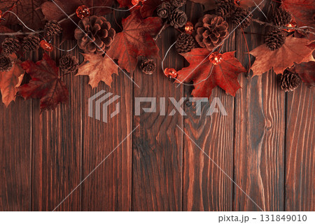 Autumn Border with Leaves, Pinecones, and Pumpkin Lights on Dark Wooden Surface Autumn Border with Leaves, Pinecones, and Pumpkin Lights on Dark Wooden Surface 131849010