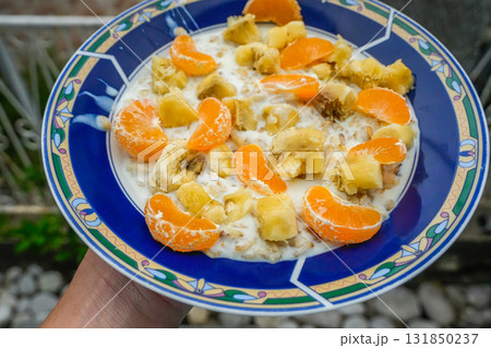 Blue plate with oatmeal, banana and mandarin slices 131850237