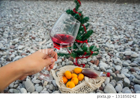 Festive beach scene with wine glass, mandarins and Christmas tree Festive beach scene with wine glass, mandarins and Christmas tree 131850242