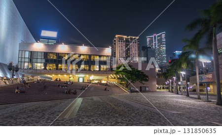 People sitting on the stairs near Hong Kong Cultural Centre with palms and towers on background timelapse hyperlapse. 131850635
