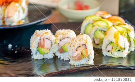 Colorful sushi rolls arranged on a black plate, showcasing fresh ingredients and vibrant presentation, perfect for culinary enthusiasts and food lovers 131850833