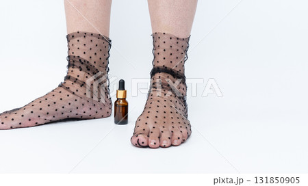Sore, heavy legs and tired feet in sheer polka dot stockings beside a small amber bottle, illustrating the concept of relaxation and self-care 131850905