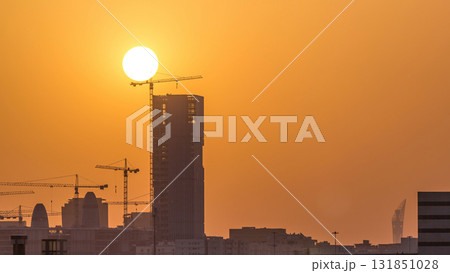 A tower in Doha timelapse, Qatar, under construction, silhouetted against the sunset. 131851028