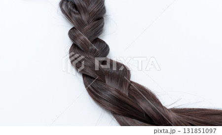 Close-up of a beautifully braided dark hair strand on a white background, showcasing intricate weaving and smooth texture, perfect for hair styling concepts 131851097