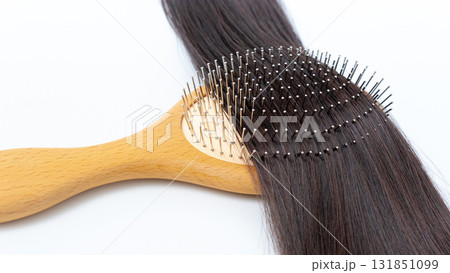 Healthy hair being brushed with a wooden hairbrush, showcasing smooth strands and the importance of hair care and maintenance for vibrant locks 131851099