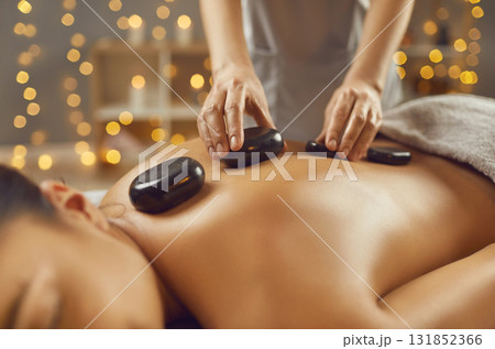 Young woman having hot stone massage in spa salon 131852366