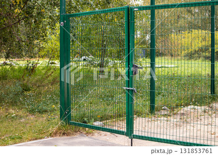 Metal mesh gate with lock and chain on green area horizontal photo Metal mesh gate with lock and chain on green area horizontal photo 131853761
