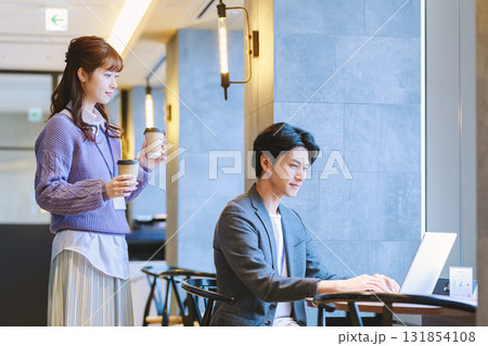 オフィスで同僚にコーヒーを勧める女性 オフィスで同僚にコーヒーを勧める女性 131854108