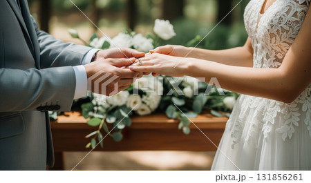 Groom placing a wedding ring on his bride finger during an intimate outdoor ceremony Groom placing a wedding ring on his bride finger during an intimate outdoor ceremony 131856261