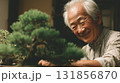 kind faced elderly man enjoys working with bonsai trees, showcasing his passion for gardening and nature. His smile reflects joy and dedication to this art form 131856870