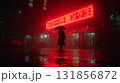 person standing under glowing red neon sign in rain, creating moody atmosphere. wet pavement reflects vibrant colors, enhancing urban night scene 131856872
