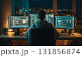 young software developer working late at night, focused on multiple screens displaying code and programming tasks. room is illuminated by glow of monitors, creating productive atmosphere 131856874