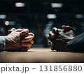 Two diverse colleagues engaged in serious negotiation, hands clasped together on table, showcasing tension and collaboration in professional setting 131856880