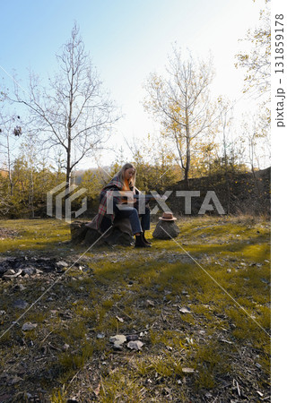 Portrait of smiling caucasian artist plays wooden acoustic guitar in autumnal park. Young songwriter plays string musical instrument hobby outside in nature fall time. Audio music healing Portrait of smiling caucasian artist plays wooden acoustic guitar in autumnal park. Young songwriter plays string musical instrument hobby outside in nature fall time. Audio music healing 131859178