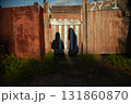 Shadows of 2 unknown people on a rustic fence. Two people stand together by a weathered wooden gate in the countryside as the sunset casts long shadows 131860870