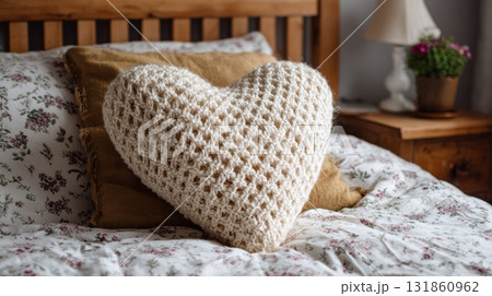 Cozy chunky knit heart pillow displayed on college dorm bed with frayed vintage crochet pattern book beside it Cozy chunky knit heart pillow displayed on college dorm bed with frayed vintage crochet pattern book beside it 131860962