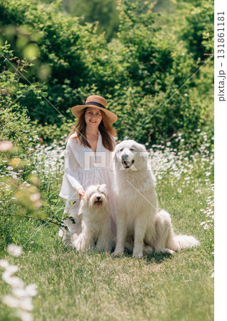 Dogs Woman Meadow: Owner poses with her dogs in a flower-filled meadow during a sunny day. Dogs Woman Meadow: Owner poses with her dogs in a flower-filled meadow during a sunny day. 131861181