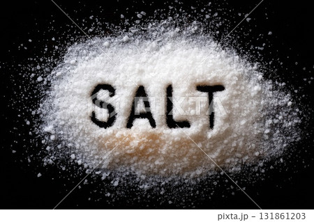 Overhead view of coarse white salt grains fully covering background with the word SALT spelled out 131861203