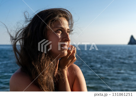 Woman, ocean, copy space. A woman relaxing by the ocean under a clear blue sky, enjoying a peaceful moment. 131861251