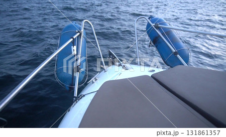 Boat water sailing. Bow of a sailboat with blue safety fenders attached, cruising over dark choppy ocean waves. Boat water sailing. Bow of a sailboat with blue safety fenders attached, cruising over dark choppy ocean waves. 131861357
