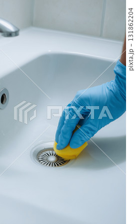 Hand scrubbing sink drain with yellow sponge in a bathroom 131862204