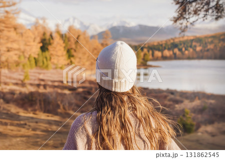 Woman enjoying a peaceful solo travel weekend by a serene lake surrounded by autumn colors in a forest landscape Woman enjoying a peaceful solo travel weekend by a serene lake surrounded by autumn colors in a forest landscape 131862545