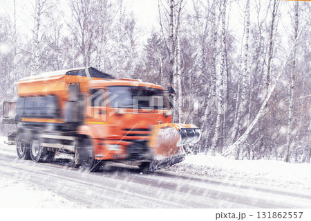 Orange-colored snow removal equipment removes snow on roads and country roads in winter during heavy snowfall. Heavy road conditions and ice . Safety and accidents on the roads. 131862557
