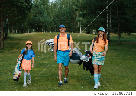 Family enjoys a fun day of golf on a sunny afternoon at a picturesque golf course surrounded by lush trees and green grass Family enjoys a fun day of golf on a sunny afternoon at a picturesque golf course surrounded by lush trees and green grass 131862711