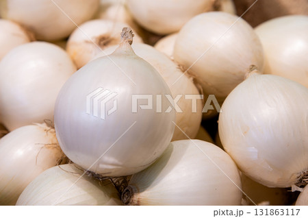 Natural fresh onions, lying in a pile, onions for sale by weight. A top-side view of the round white bulbs, clean vegetables 131863117