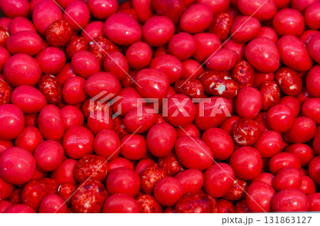 Hazelnut dragees in sugar glaze. Close-up of hazelnut candies. A background of a pile of nuts covered in bright red glaze 131863127