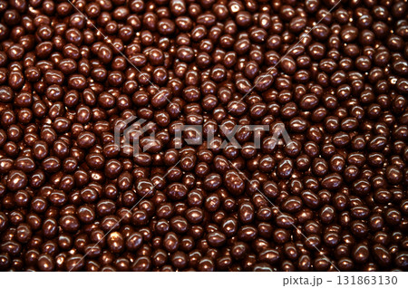 large quantity of chocolate-covered hazelnuts or raisins, the photo can be used as a background. Chocolate-covered nuts make a beautiful, shiny, sugary snack large quantity of chocolate-covered hazelnuts or raisins, the photo can be used as a background. Chocolate-covered nuts make a beautiful, shiny, sugary snack 131863130