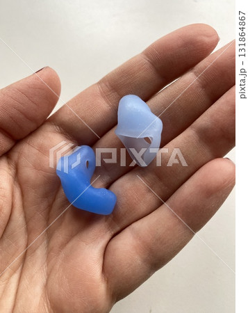 Custom silicone earplugs resting on an open palm, providing noise protection and comfort 131864867