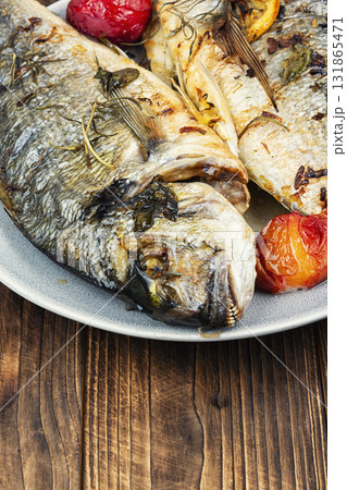 Grilled dorado fish with plums on wooden surface. 131865471