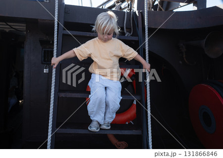 Little 4 year old girl exploring a ship and carefully going down the stairs 131866846
