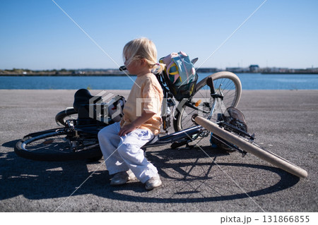 Girl sitting alone on bicycles waiting for her parents. breakdown during a trip Girl sitting alone on bicycles waiting for her parents. breakdown during a trip 131866855
