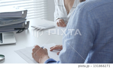 Professional team collaborating, reviewing financial reports, using calculator, analyzing data while working at sleek corporate workspace. Audit and taxes in business 131868271