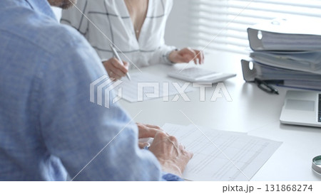 Accounting team working together, reviewing financial reports, using calculator, analyzing data while working at sleek corporate workspace. Audit and taxes concept Accounting team working together, reviewing financial reports, using calculator, analyzing data while working at sleek corporate workspace. Audit and taxes concept 131868274