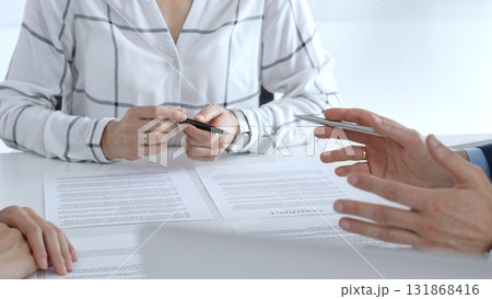 Business professionals or lawyers sitting at the desk in a bright office, reviewing and discussing contract papers. Teamwork concept 131868416