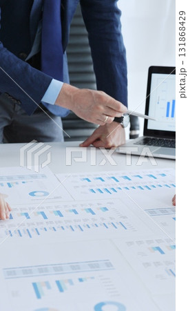 Business professionals analyzing financial data and market trends during a corporate meeting, collaborating on reports and developing strategic investment plans 131868429