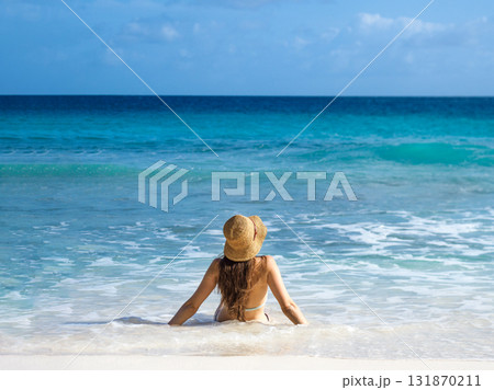 Cute woman sitting on stunning white sand beach 131870211