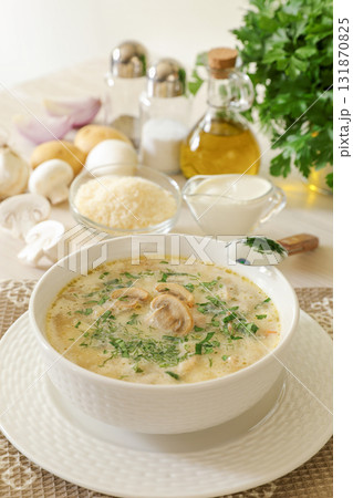 Tasty champignon mushrooms soup with cream and cheese in white bowl on white wooden background. Healthy food still life. 131870825