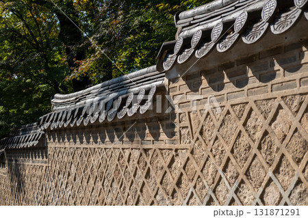 Korean traditional stone wall in Changdeokgung palace with shadow and beautiful autumn foliage. 131871291