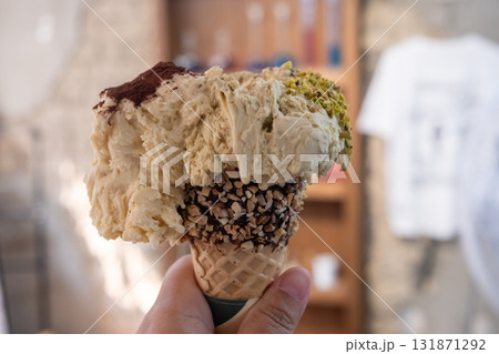 Hand holding Pistachio and Tiramisu Gelato, Ice-cream with waffle cone Hand holding Pistachio and Tiramisu Gelato, Ice-cream with waffle cone 131871292