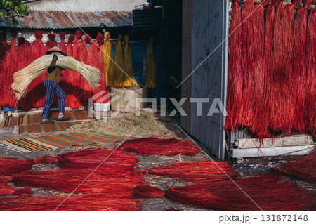 Vietnamese woman in a traditional straw hat dries dyed reeds for production of woven mats at factory in an artisan village in Vietnam Vietnamese woman in a traditional straw hat dries dyed reeds for production of woven mats at factory in an artisan village in Vietnam 131872148