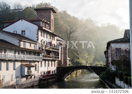 朝もやの中の川沿いに立つ歴史的な建物と木々　フレンチバスク地方のサン・ジャン・ピエ・ド・ポールにて 131872506