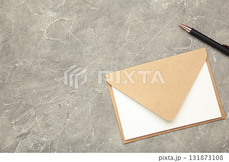 Craft envelope with paper card and pen on grey concrete background. Space for text Craft envelope with paper card and pen on grey concrete background. Space for text 131873108