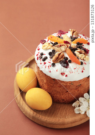 Traditional easter cakes with colorful sprinkles, with eggs and spring flowers on brown background. Traditional easter cakes with colorful sprinkles, with eggs and spring flowers on brown background. 131873126